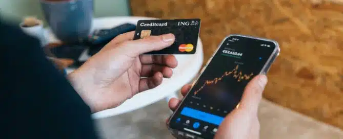 Person holding a credit card and checking credit score on a smartphone.