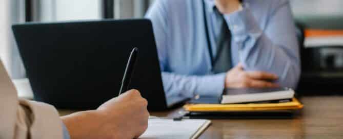 A business loan consultation with one person taking notes while the other discusses loan options and terms.